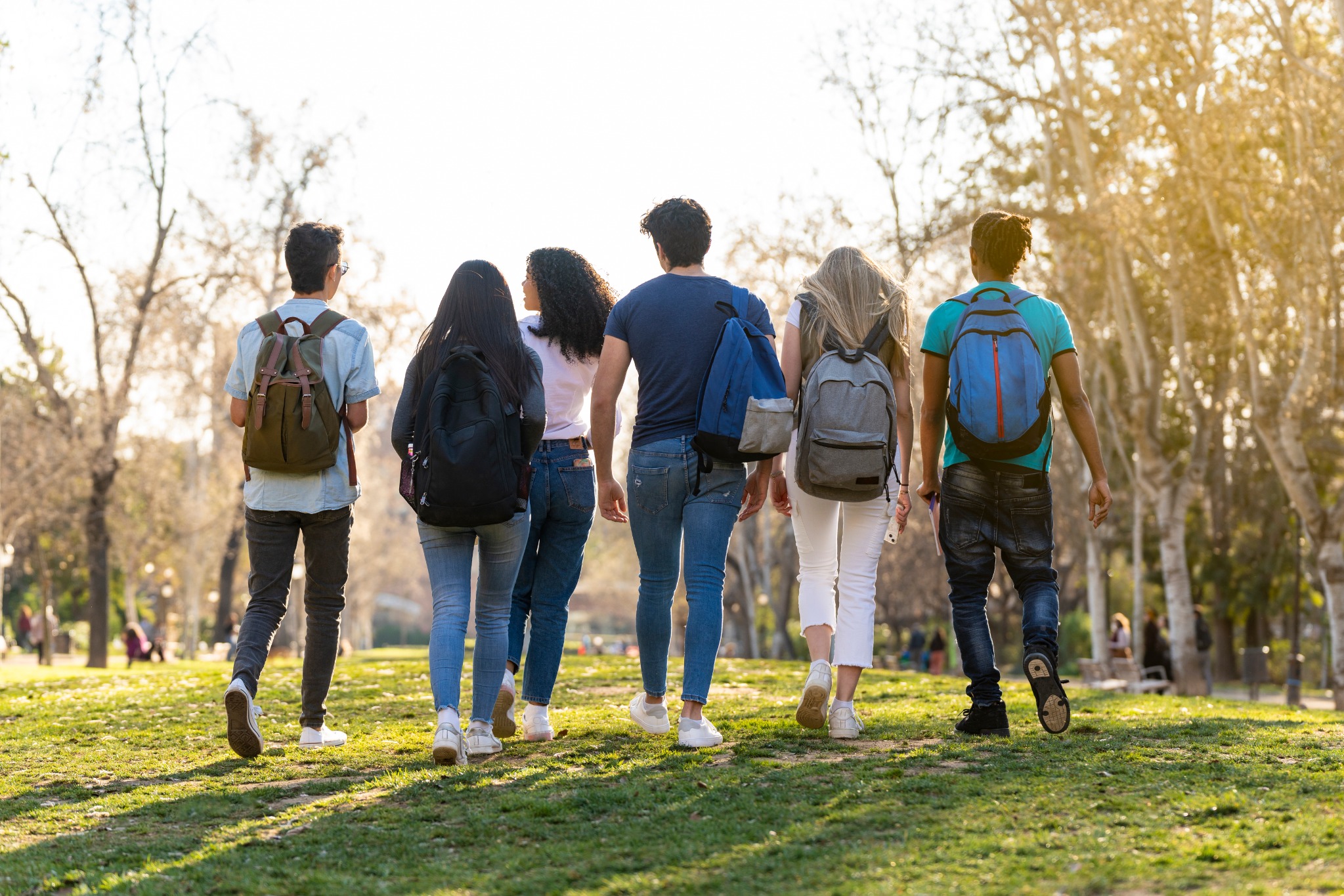 Group of teenagers walking together outdoors in a sunlit park