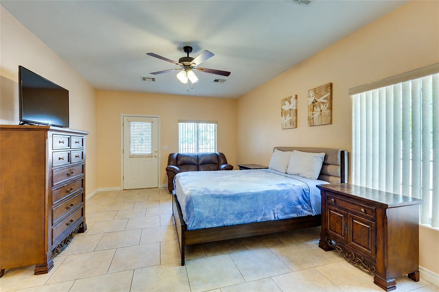 Bedroom at Rise with a bed, wood furnishings, and a small seating area.